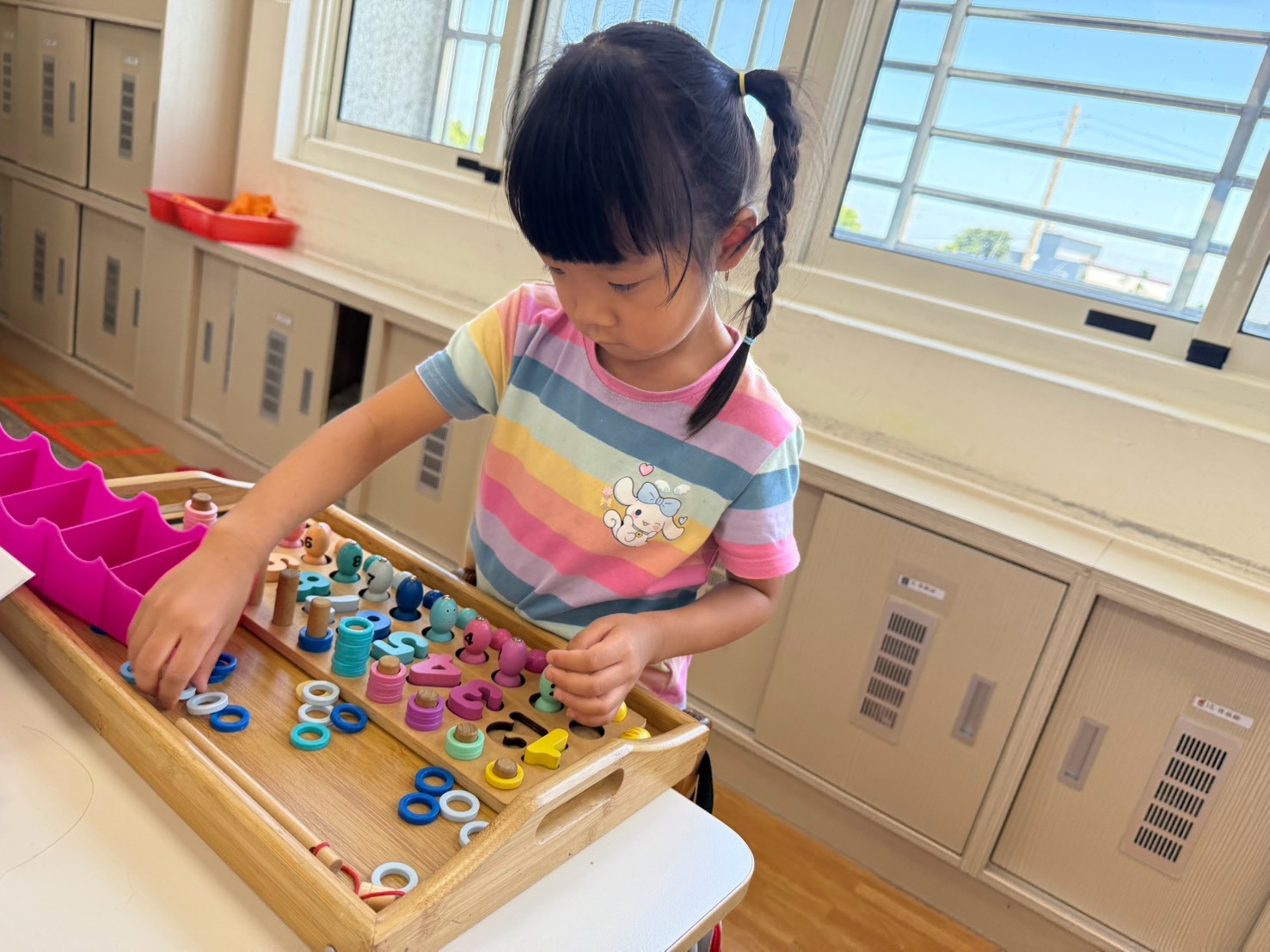 女孩正在操作數字符號、套圈圈與色彩排序的數概念教具。