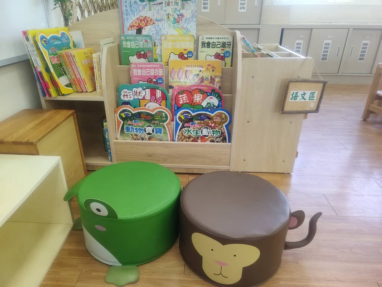 設有階梯式書架，陳列《我會自己刷牙》、《蔬菜水果》、《動物寶寶》等繪本，並配有青蛙與猴子造型的可愛小靠椅。